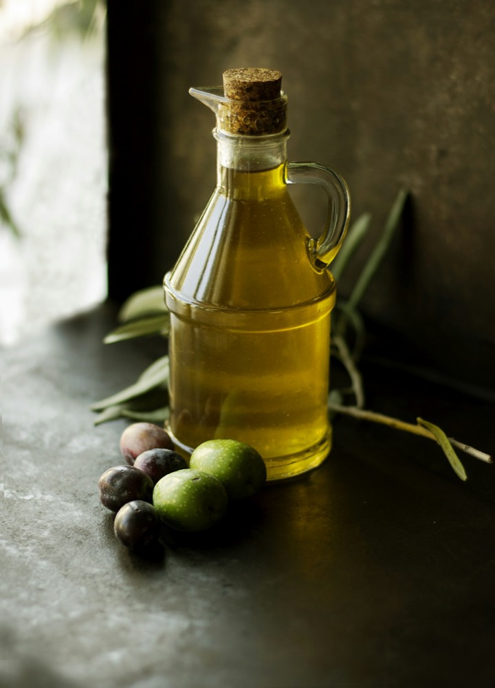 A bottle of olive oil with olives